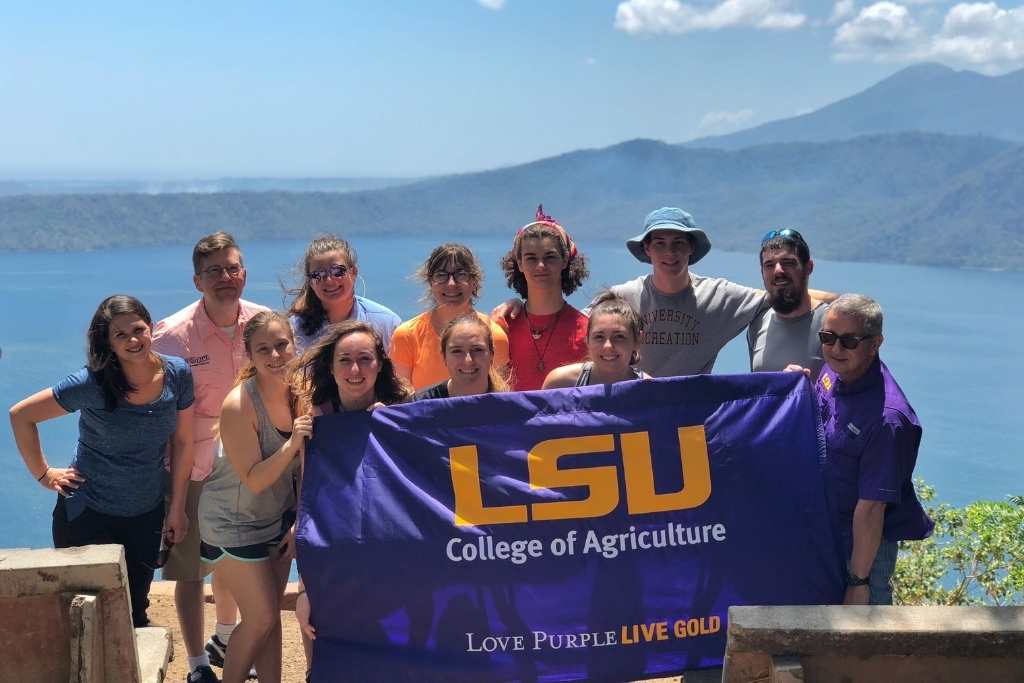 students hold LSU flag by beach