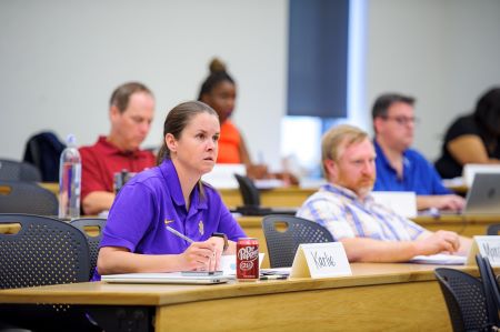 woman takes notes in class