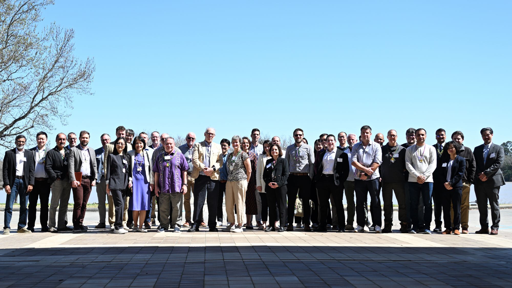 Large group of people stand for a photo in front of a lake