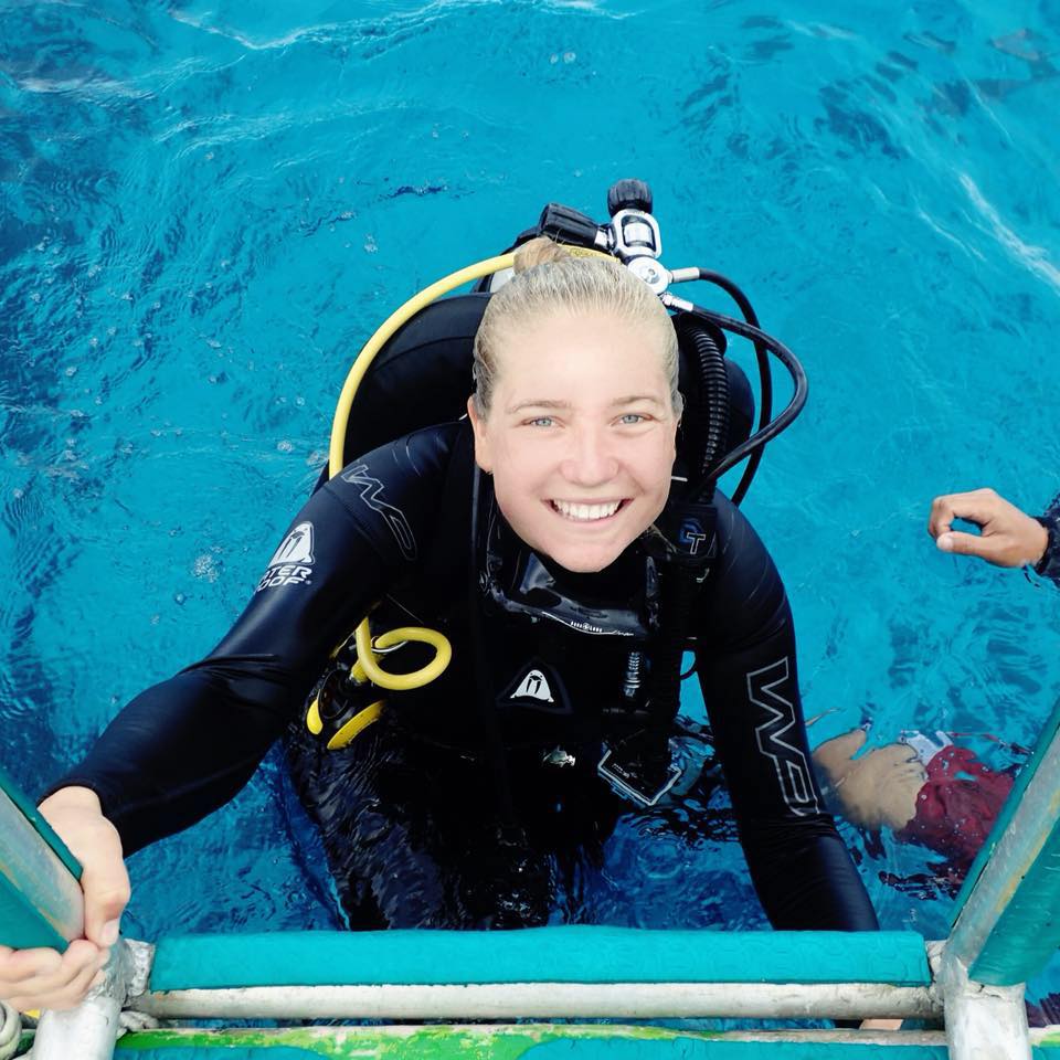 a woman in a scuba diver suit walks out of the water onto a ladder