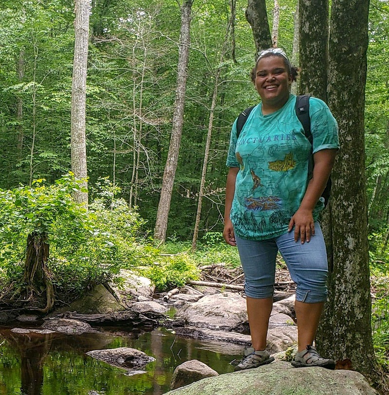 Nicole Hammond stands on a rock in the woods