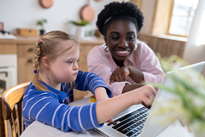 Teacher working with a young girl on the computer.