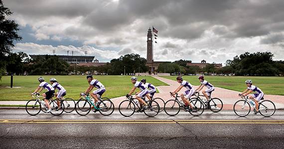 LSU Cycling Club riding in front of the Parade Gounrds with the Memorial Tower in the background