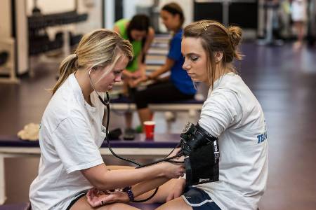 image of one girl taking blood pressure of another
