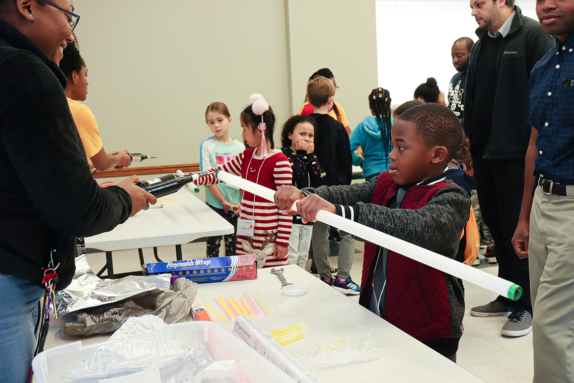 STEM Story Time participant doing a hands-on acitivity with a LSU College of Science student.