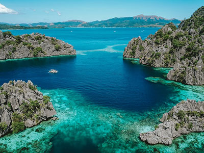 Overlooking a small bay of crystal clear light blue water in the Philippines by John Hernandez on Unsplash.