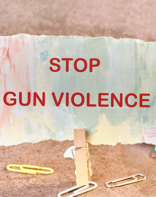 Photo of a clothes pin holding a colorful piece of paper with the words Stop Gun Violence on it.