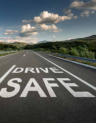 Photo of a road with the words drive safe in white.