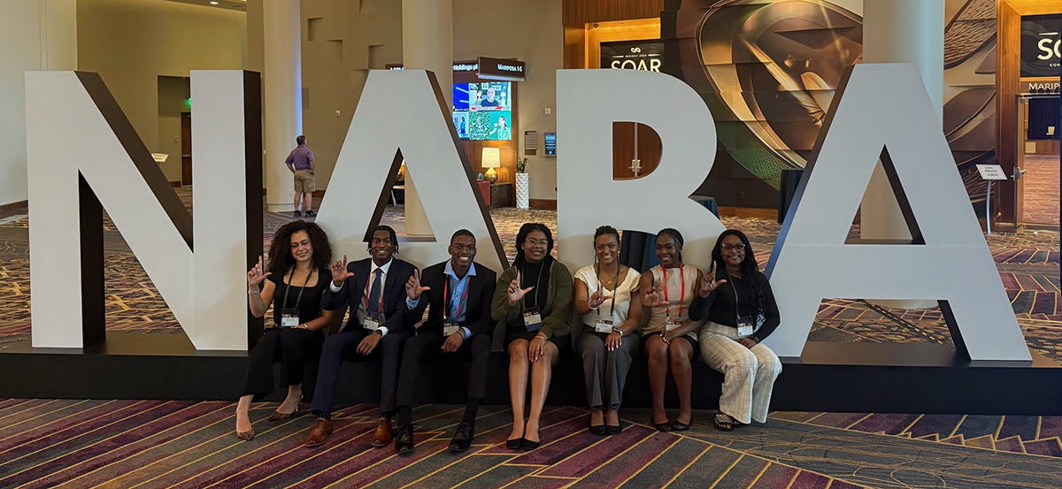 students in front of a large NABA sign