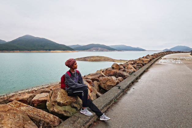 Female student sit on rock side of road in Hong Kong
